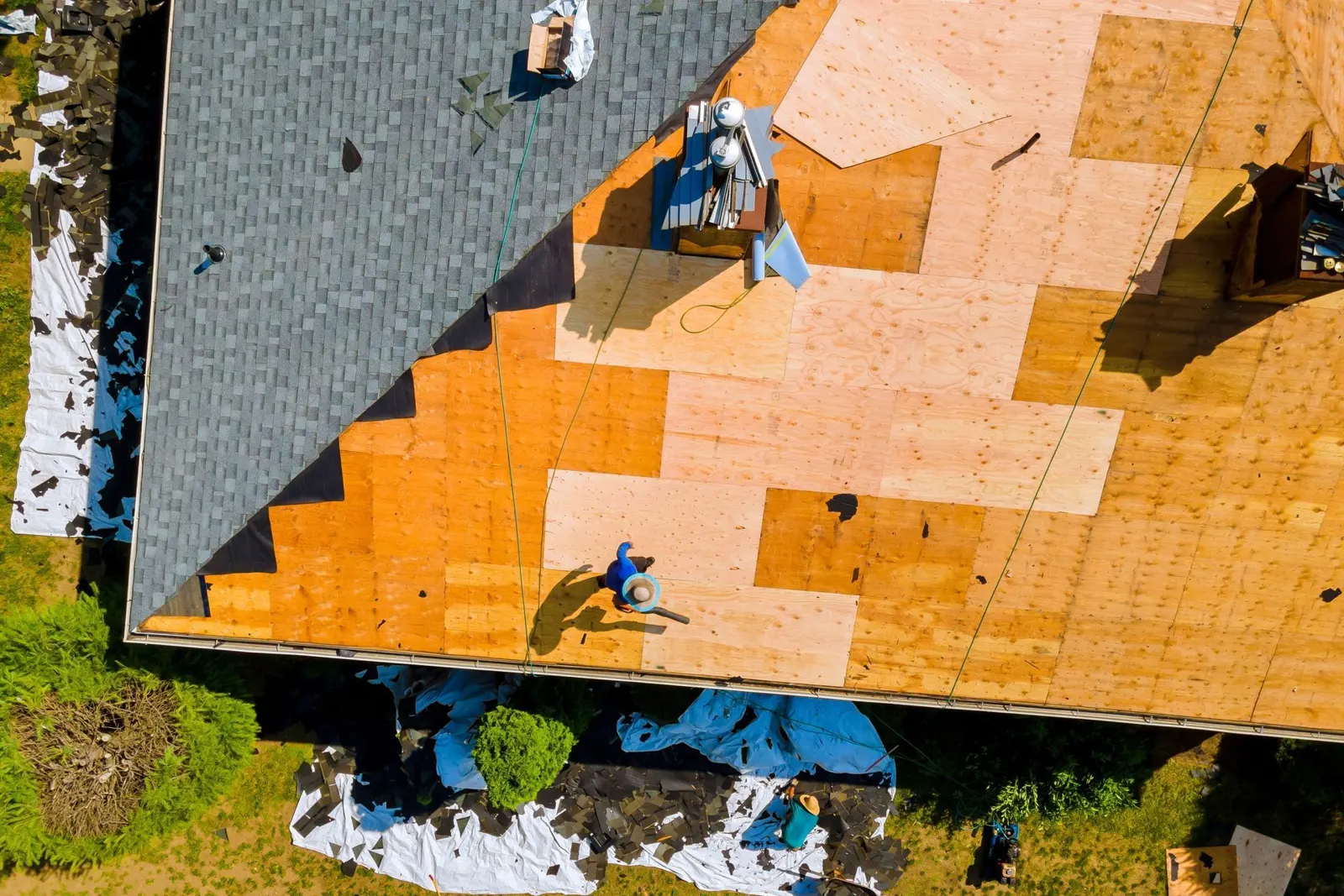 Roofers installing new decking and shingles on a house roof